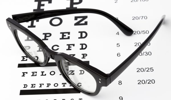 Reading glasses with eye chart isolated on white.