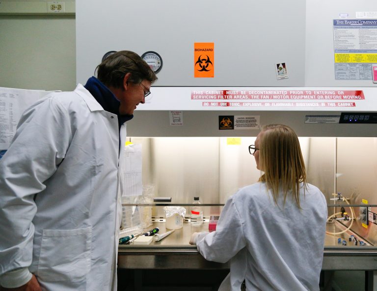 Robert Nickells, PhD, oversees a student's pipetting under the safety hood.