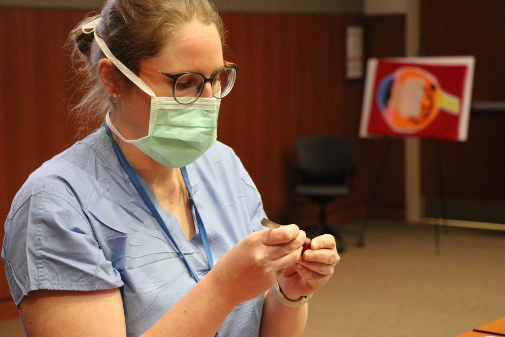 Ophthalmologist Jennifer Larson demonstrates a surgical technique on a grape.