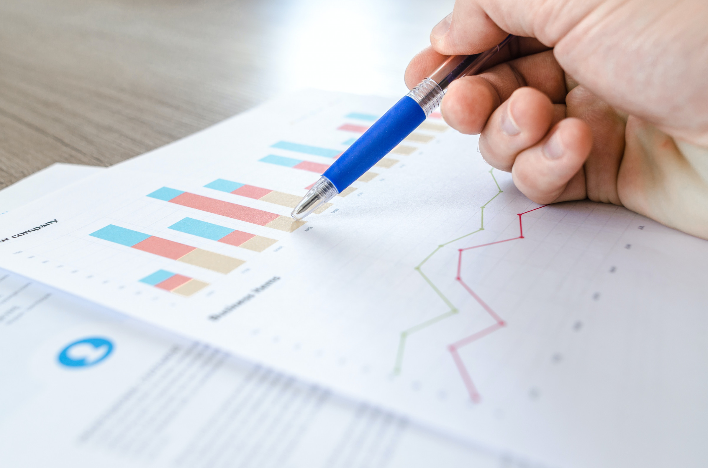 Person holding ballpoint pen over research graph