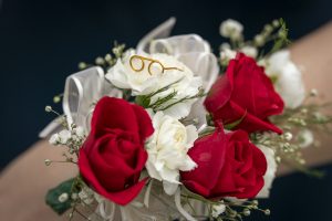 Red and white corsage with a tiny gold glasses pendant. 