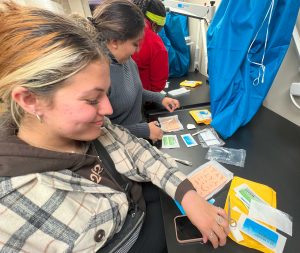 a woman in a plaid shirt practices sutures