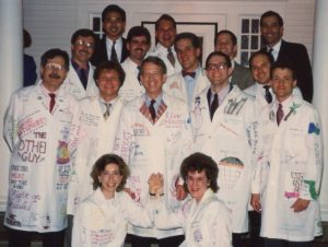 group of men and women in white doctor's coats decorated with colorful signatures and drawings