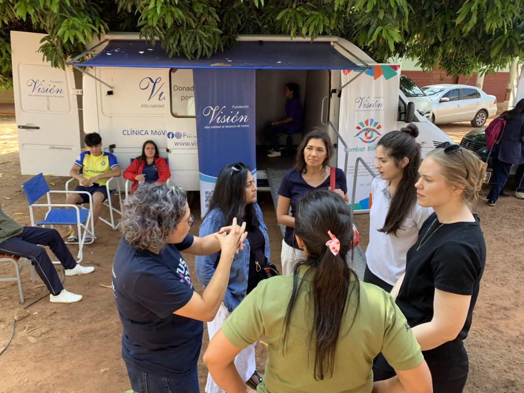 a small group of women gathers in front of a mobile medical van