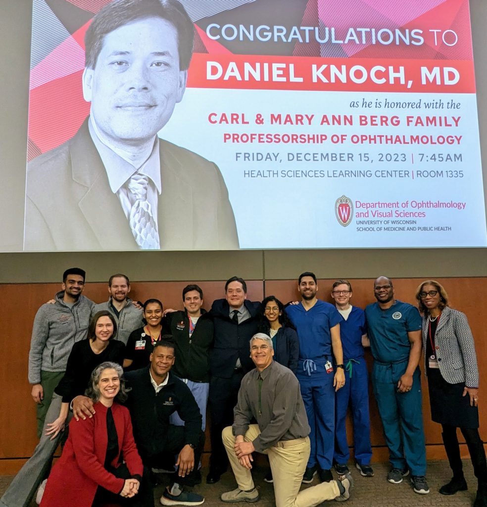 Faculty, residents, and guests in front of a celebratory poster