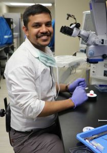 man sits in front of a microscope