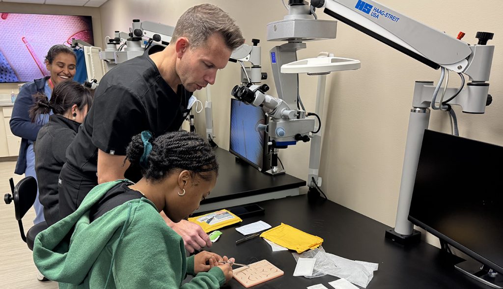 an instructor helps a student with a suture