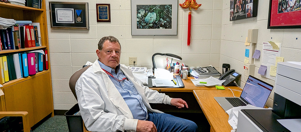man in a white lab coat sitting behind a desk