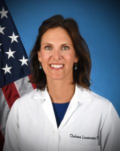 a doctor stands in front of an American flag