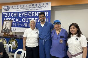 four people in front of a Tzu Chi Eye Center banner