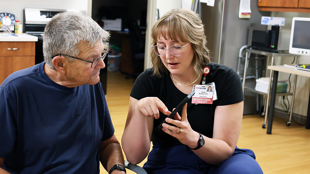 a woman in a black shirt and a man in a blue shirt look at a cell phone