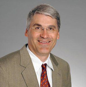 man in a tan suit and red tie