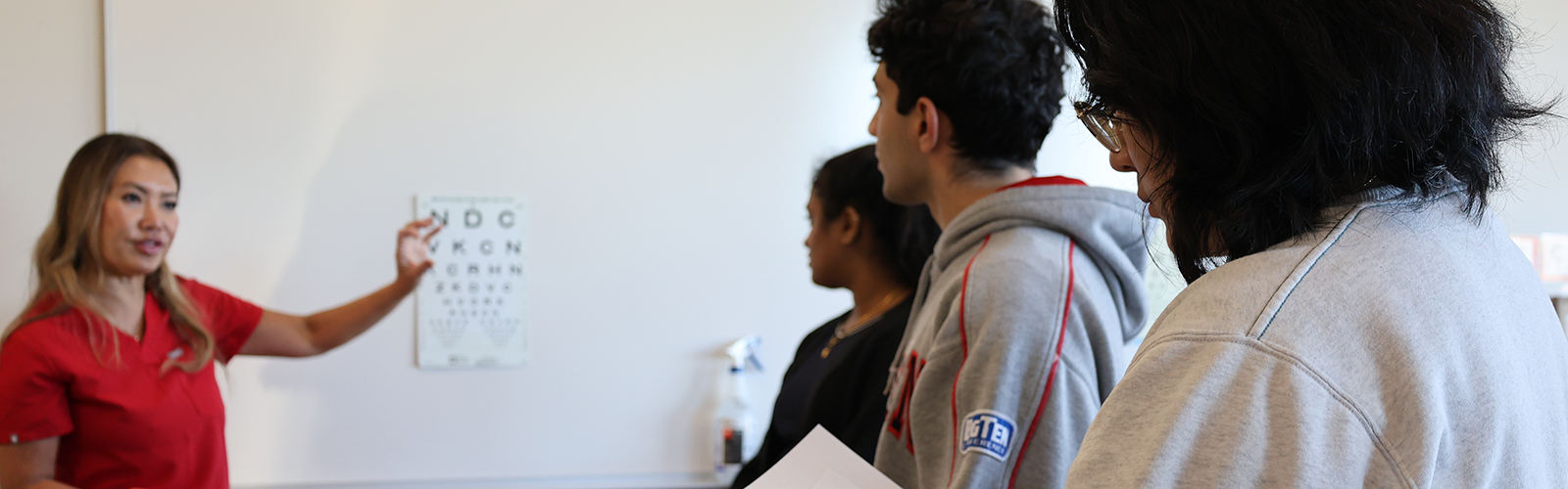 Dr. Cat Burkat reviews vision screening steps with medical student volunteers during local school screening day.
