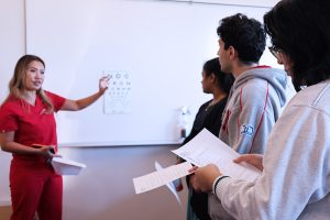 Dr. Cat Burkat reviews vision screening steps with medical student volunteers during local school screening day.