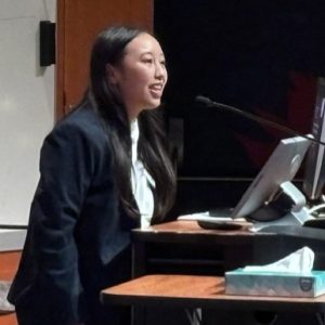 woman in a black suit at a podium