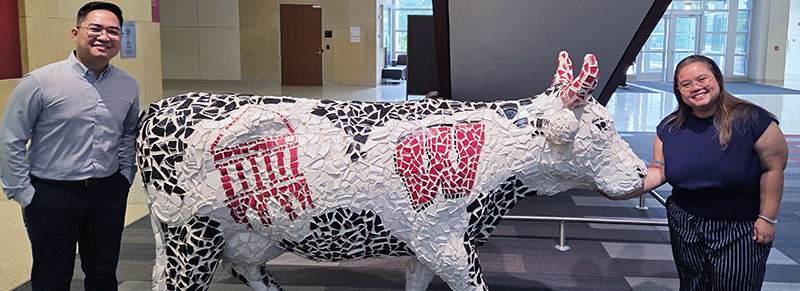 two people next to a cow statue