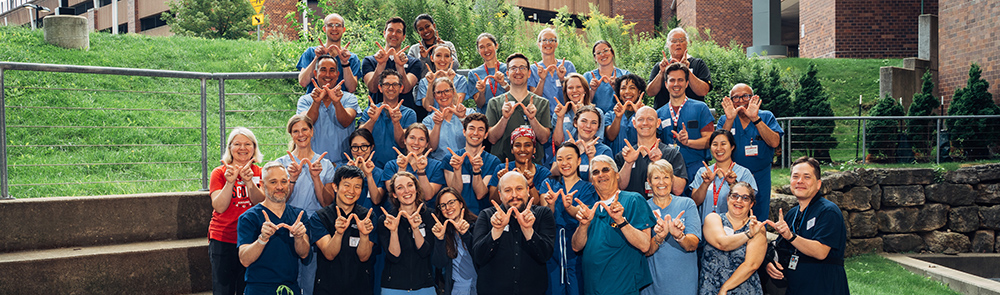 large group in scrubs making the 'w' with their hands